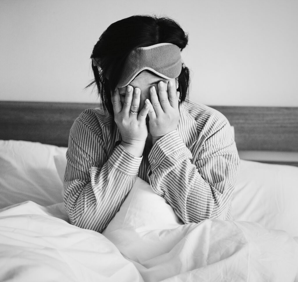 Woman sitting in bed feeling exhausted and overwhelmed, showing sleep struggles as signs you need depression therapy